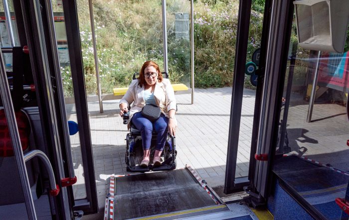 Mujer en silla de ruedas subiendo a un autobús urbano adaptado con rampa